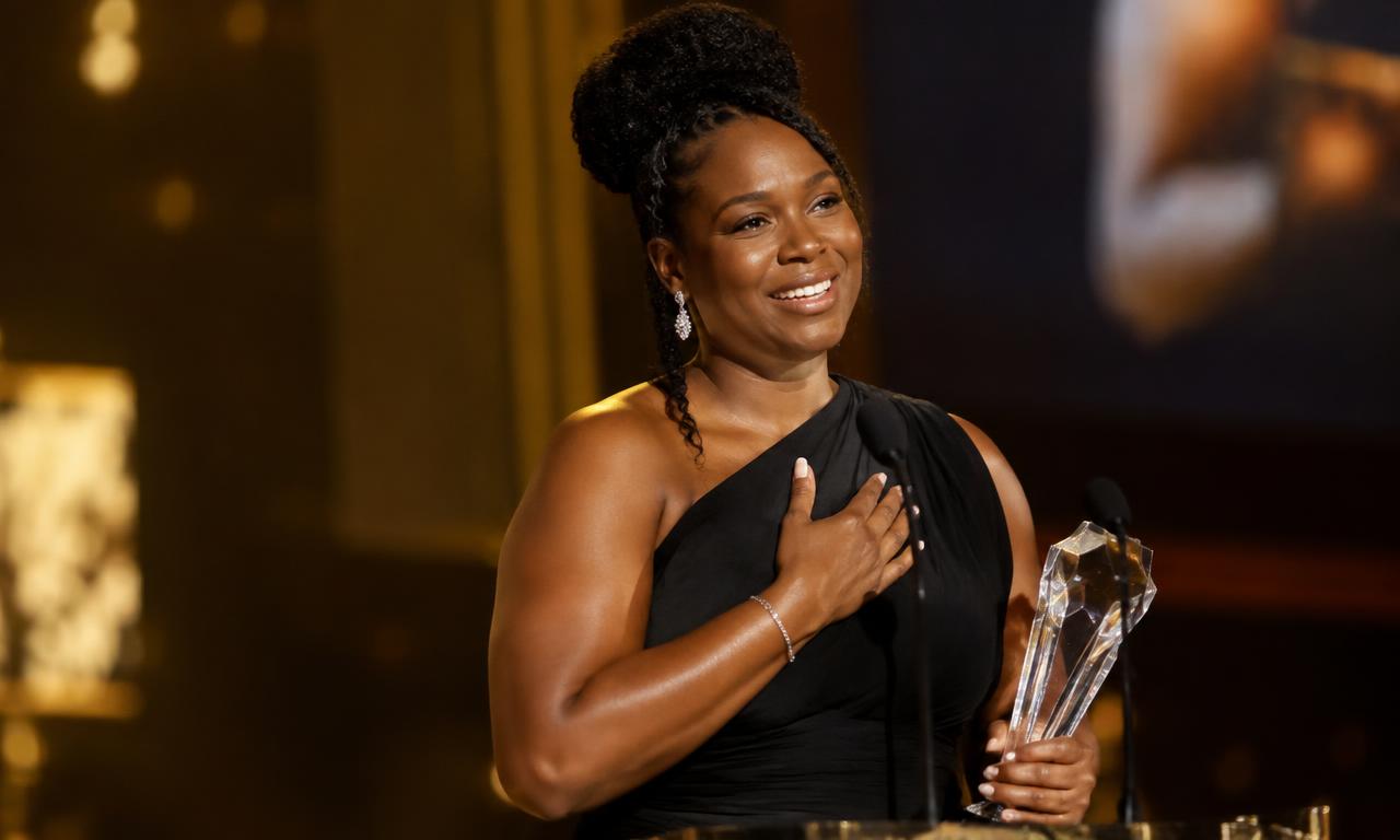 Award recipient speaking on stage while holding a glass award