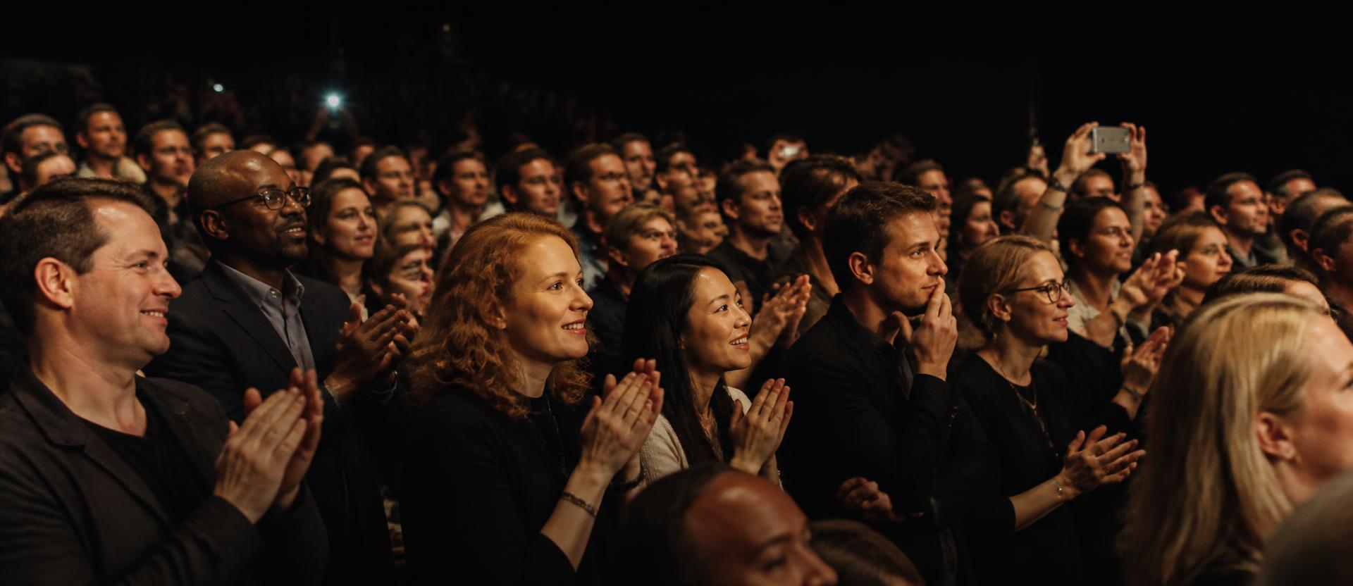 Wide view of an audience applauding at an evening event